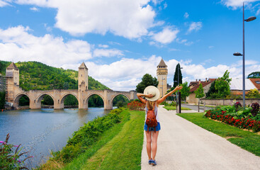 Woman traveling in France-Lot, Cahors city landscape with river and bridge - obrazy, fototapety, plakaty