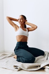 Fototapeta premium A woman poses sitting on her knees on the floor with beautiful tanned skin and long brown hair and smiling
