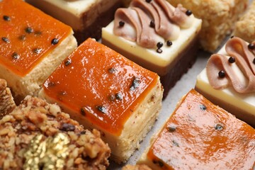 Pieces of different delicious cakes on table, closeup