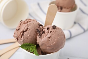 Paper cup with tasty chocolate ice cream on white table, closeup