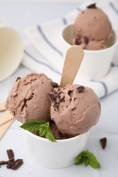 Paper cups with tasty chocolate ice cream on white table, closeup