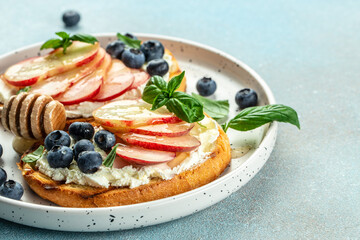 Delicious toast with cream cheese, honey, peaches and blueberries. Concept healthy and balanced eating. place for text, top view