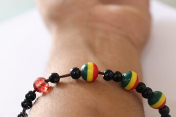 A Jamaican or African Rasta Charm bracelet in the hand or forearm with selective focus on an isolated White background 