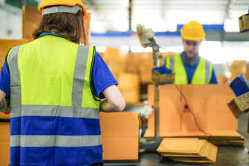 Warehouse worker folding paper box for packing the items in a large warehouse. man sealing...