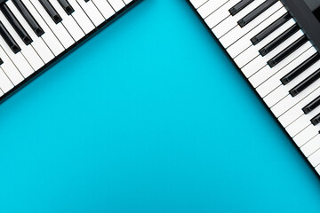 Top view of piano keyboards with copy space. Minimalist photo of midi keyboards over blue. Two piano style keyboards on turquoise background.