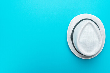 Top view of trilby over turquoise blue background. Flat lay top-down composition of white trilby hat. Minimalist flat lay photo of white hat with copy space.