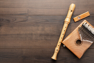 Overhead photo of kazoo, recorder and kalimba with copy space. Flat lay top-down composition of wooden musical instruments on the wooden background.