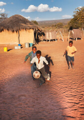 African village children playing football on the dirt in the yard
