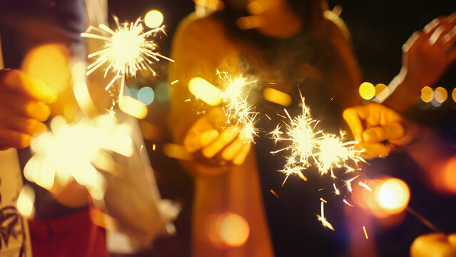 Group of Asian young man and woman having party on the beach at night.group of happy young Asian sitting and playing sparklers together with bokeh on tropical island beach at summer night. - Powered by Adobe