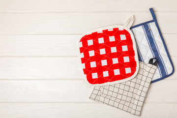 Wooden kitchen utensils, cutting board, potholder and glove on the table, top view. Kitchen Mitten...