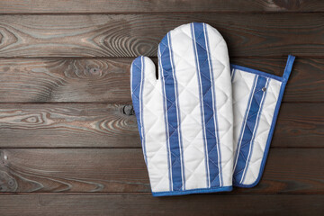 Wooden kitchen utensils, cutting board, potholder and glove on the table, top view. Kitchen Mitten...