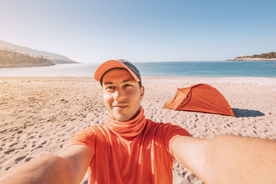 spirit of adventure along the Lycian Way as a man hiker taking selfie photo against camping tent in the sandy beach, on a sea coast