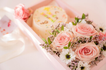 Obraz na płótnie Canvas Cake with blooming roses in a pink gift box on a white background.