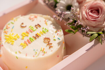 Cake with an inscription with blooming roses in pink gift box.