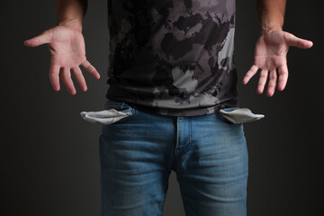 Man in T shirt and jeans with turned out, empty pockets.Concept of bankruptcy and poverty.