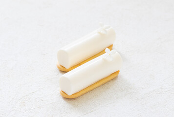 Two Vanilla cream desserts in the form of a candy bar, decorated with a small white flower. On cookies. White background