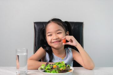 Obraz na płótnie Canvas Little asian cute girl to eat healthy vegetables.Nutrition and healthy eating habits for kids concept.Children happy and like to eat vegetables.
