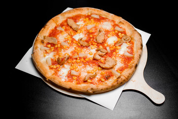 Pizza Americana with mozzarella cheese, chicken fillet, pineapple and sweet corn served on wooden board