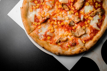 American pizza with tomato sauce, mozzarella cheese, corn, chicken and pineappleserved on wooden board