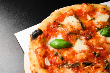 Appetizing Neapolitan pizza with anchovy, capers, mozarella cheese sprinkled with garlic chips and...