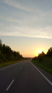 Driving along a rural road at sunset, vertical