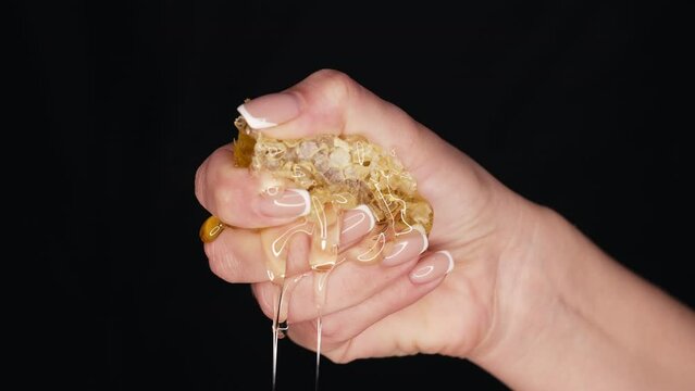 Woman hand squeezes honeycombs full of honey. Dripping,pouring tasty sweet fluid