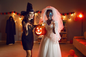 Portrait of scary women in costumes on Halloween masquerade at home. Young females girls celebrate...
