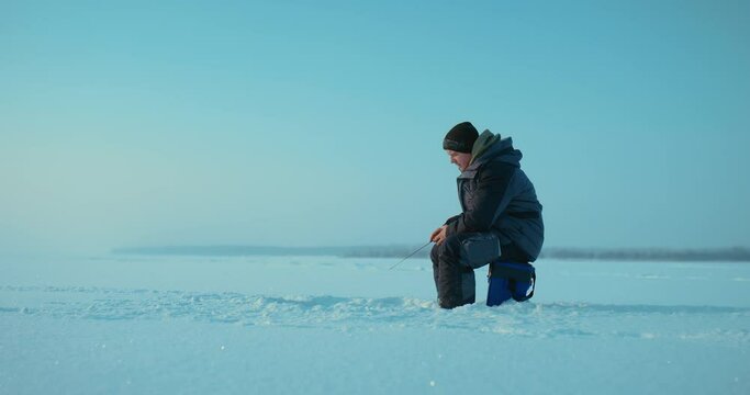 calm and meditative ice fishing process, fisherman sitting on tackle box and wait bite, 4K, Prores