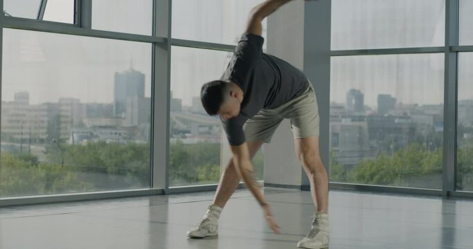 Portrait of young muscular sportsman training in gym doing full body warm-up exercising alone. Modern youth and healthy lifestyle concept.
