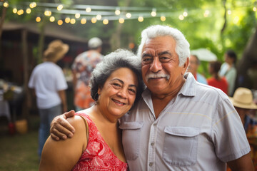 Portrait of a happy smiling Mexican senior couple at family gathering outdoors	