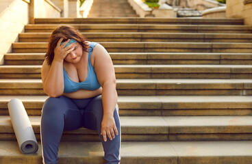 Obraz premium Tired chubby overweight woman in sportswear with fat belly and fitness mat sitting on stone stairway steps outside gym, holding hand on head, feeling stressed, sad and exhausted. Sport fatigue concept