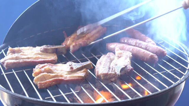 Cuoco gira la carne sulla griglia fumante