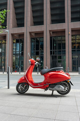 Red vintage scooter parked on a sidewalk. The moped is parked on the sidewalk in the business center of Frankfurt am Main.
