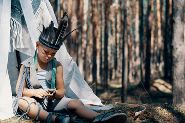 Boy dressed as an American Indian plays in the forest © Iryna Burmii