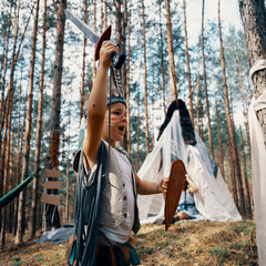 Kids dressed as an American Indians play in the forest