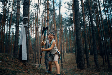 Boy dressed as an American Indian plays in the forest