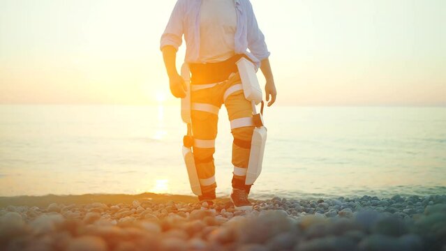 a happy man uses a mobile exoskeleton to move along the beach solving the problem of paralysis