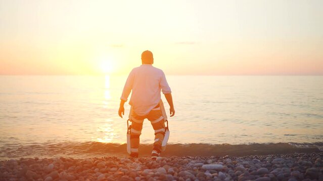 figure of a male winner raises his hands at sunset in an exoskeleton suit solving the problem of limited mobility in paralysis