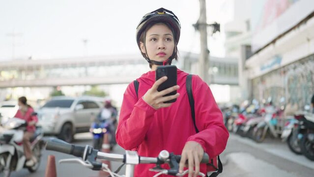 delivery Asian woman with red backpack rides a bicycle through the city with food delivery,Food delivery concept