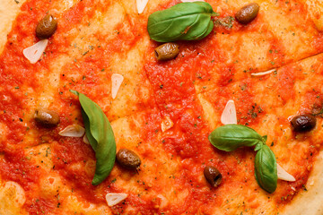 Closeup view on fresh baked Italian pizza marinara. Delicious pizza with tomato sauce, basil, garlic chips and olives.