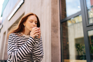 Low-angle view of young happy woman enjoy fragrant drink in cafe closed eyes. Pretty relaxed female...