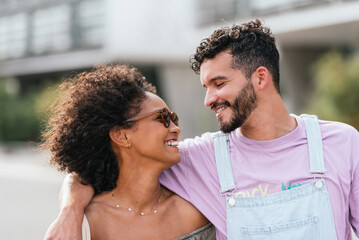 Cheerful multiethnic couple hugging on city street