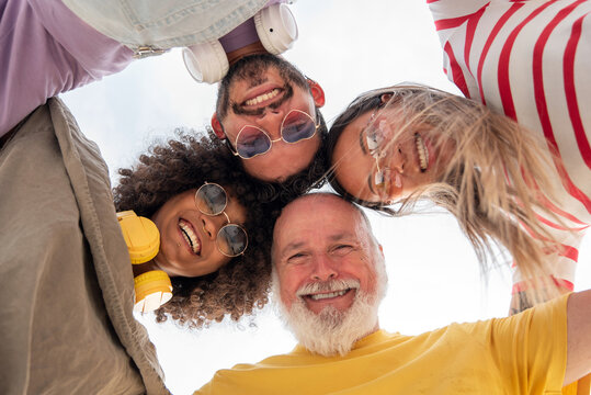 Low angle of excited diverse family hugging and looking at camera