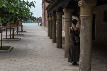 Una donna sola davanti a un colonnato di Venezia osserva il canale della Giudecca