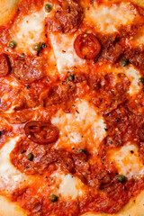 Closeup view of freshly baked appetizing mexican pizza with pepperoni, cheese , green beans and red chili peppers