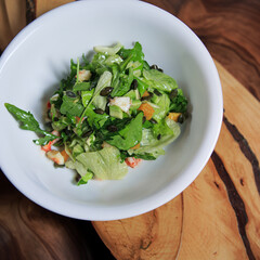 salad with lettuce, shrimp and orange in a deep white bowl on a wooden board