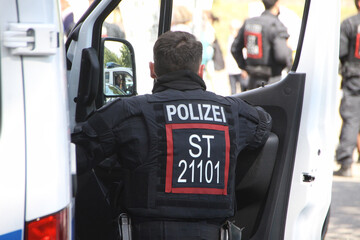 Ein Polizist der Landespolizei Sachsen-Anhalt steht in Uniform an der Tür eines Mannschaftwagens....