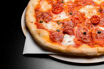 Close up view on backlited freshly baked mexican pizza with pepperoni and red chili peppers on wooden serving board