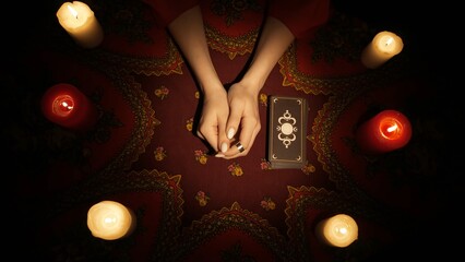 Top view, female hands on the table, deck of tarot cards laying next to her.