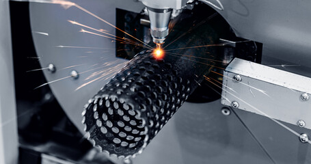 CNC industrial Automatic laser cutting machine for metal profile, splashes of bright sparks.